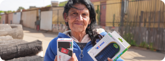 Mujer mayor sosteniendo cargador solar y celular en sus manos