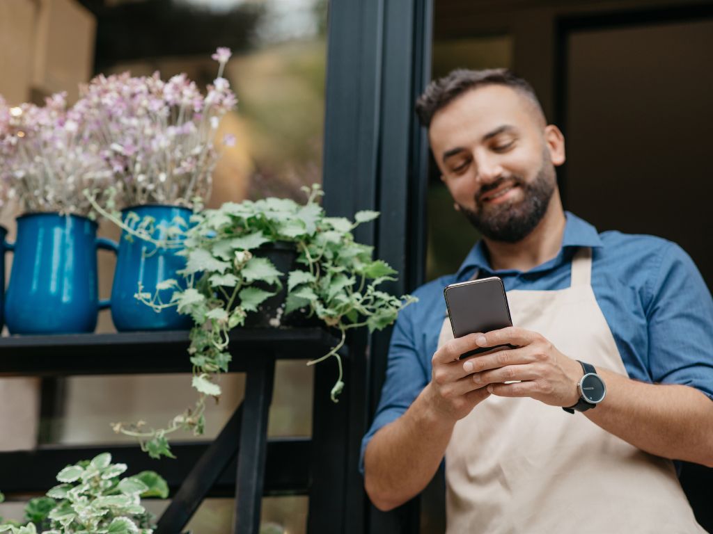 Dueño de una pyme buscando en su celular cuál es el mejor internet móvil para empresas. 
