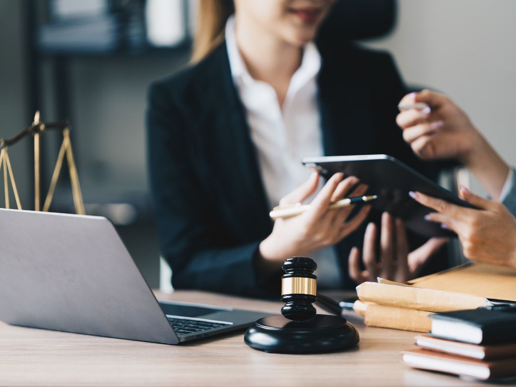 Equipo jurídico utiliza IA para abogados al revisar contratos y documentos legales con tablet y notebook. 